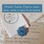 Storia Instagram pubblicata dalla scrittrice Giovanna Ceriotti con la dedica "Grazie, Lucia. Come a casa, anzi, come a casa di un'amica", che mostra un biglietto di benvenuto e un ciondolo artigianale a forma di presentosa abruzzese al B&B La Dimora di Tommaso a Ortona